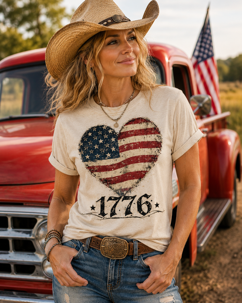 Woman wearing a t-shirt with an American flag design and cowboy hat in front of a red truck.